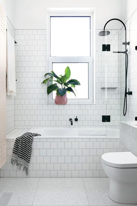 29 a white Scandinavian bathroom done with square tiles, a tub clad with tiles, black fixtures and a floating vanity