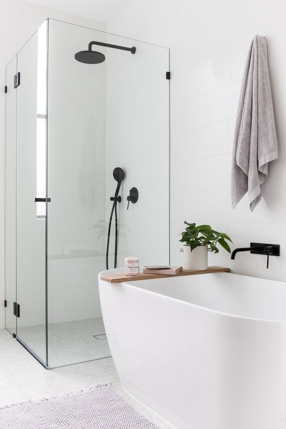30 a small and serene bathroom in white, with a shower space and an oval tub, with black fixtures is chic