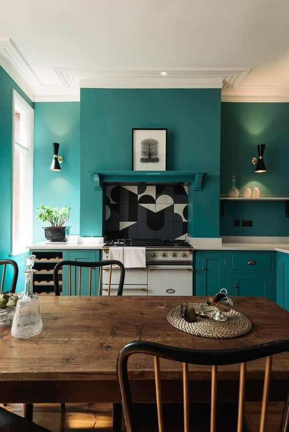 30 a teal kitchen with chic cabinets and matching walls for a sleek look, white stone countertops and a dining zone with vintage furniture