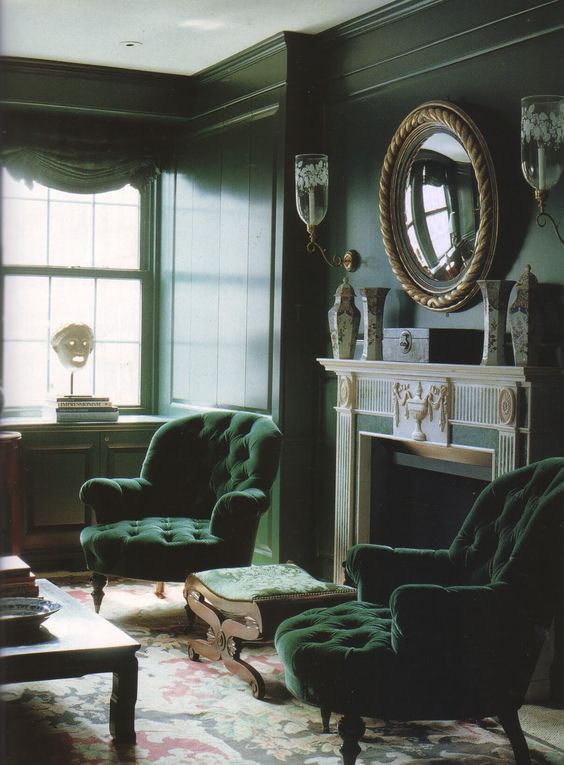 31 a moody living room in dark greens, with refined furniture, a fireplace, a large mirror and vintage vases