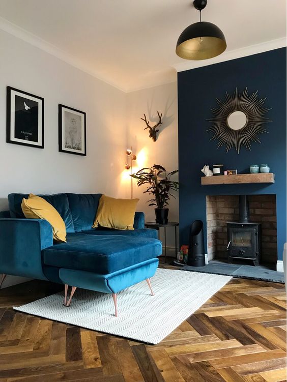 32 a pretty and stylish living room with navy furniture, a navy accented wall with a hearth and touches of gold is pretty