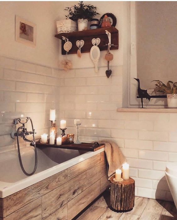 32 a pretty bathroom clad with white tiles and with wood print ones, with a tree stump and candles everywhere