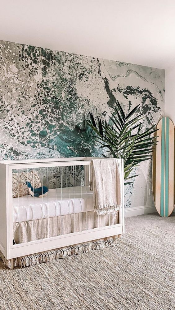 A surfing nursery with a unique water inspired wall mural, a neutral crib and a surfing board
