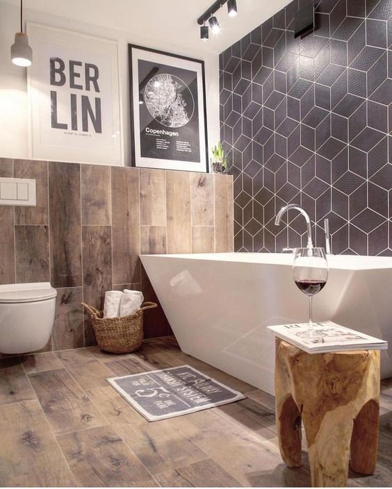 a chic bathroom with a navy geo tile wall, wood print tiles, a sculptural bathtub and a tree stump