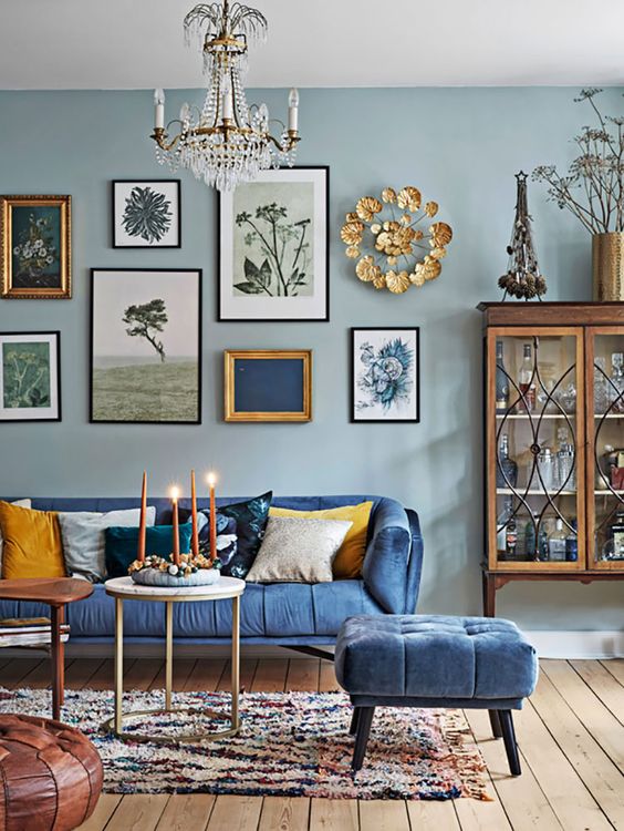 a vintage-inspired blue living room with light walls, bold furniture, a gallery wall with various artworks and gold touches