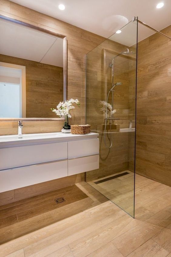 A contemporary bathroom fully clad with wood, with a white floating vanity and built in lights