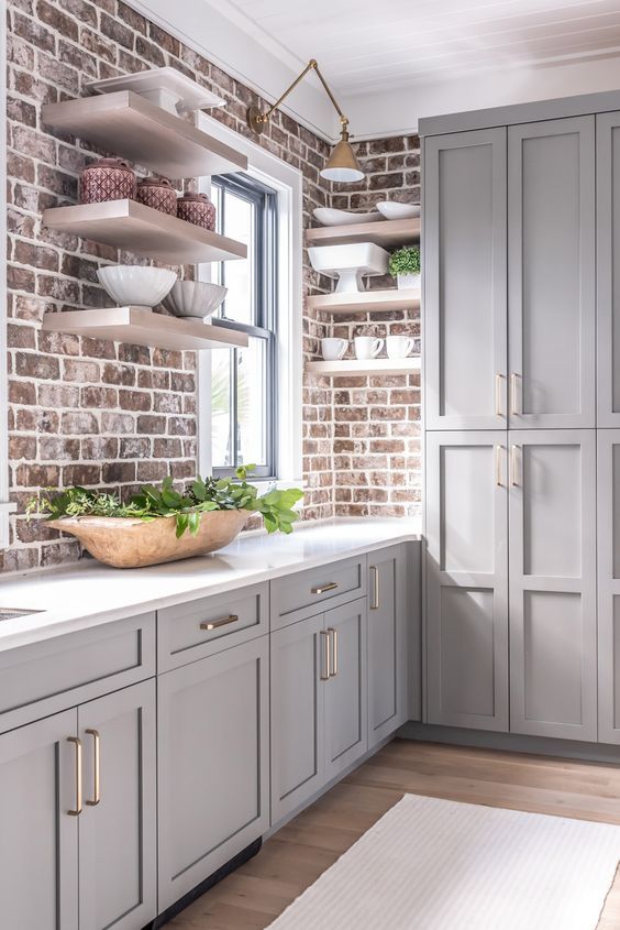 35 an elegant grey farmhouse kitchen with vintage-inspired cabinets, brick walls and a white stone countertop