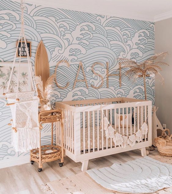 an ocean wave nursery with a bleu wave print wall, neutral furniture, baskets and a rattan cart for storage
