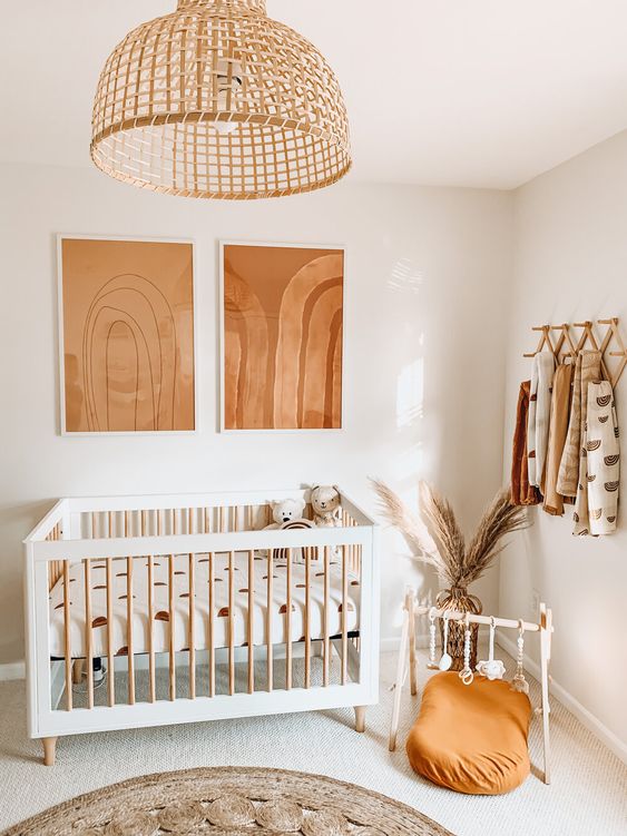 a neutral nursery with rust and orange touches, printed textiles, a rattan pendant lamp and pampas grass