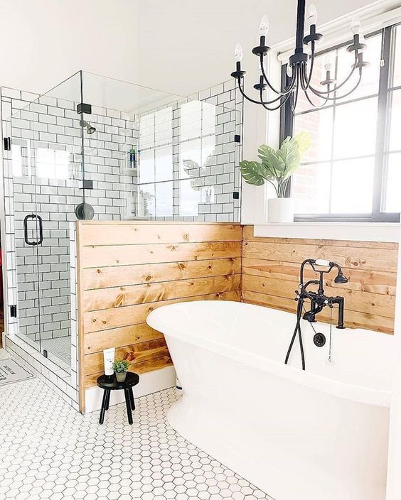 38 a farmhouse bathroom with white subway and hex tiles, wooden panels, a vintage bathtub and vintage chandeliers