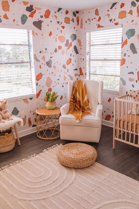 A pretty nursery with terrazzo walls, earthy and light colored furniture and accessories and potted plants