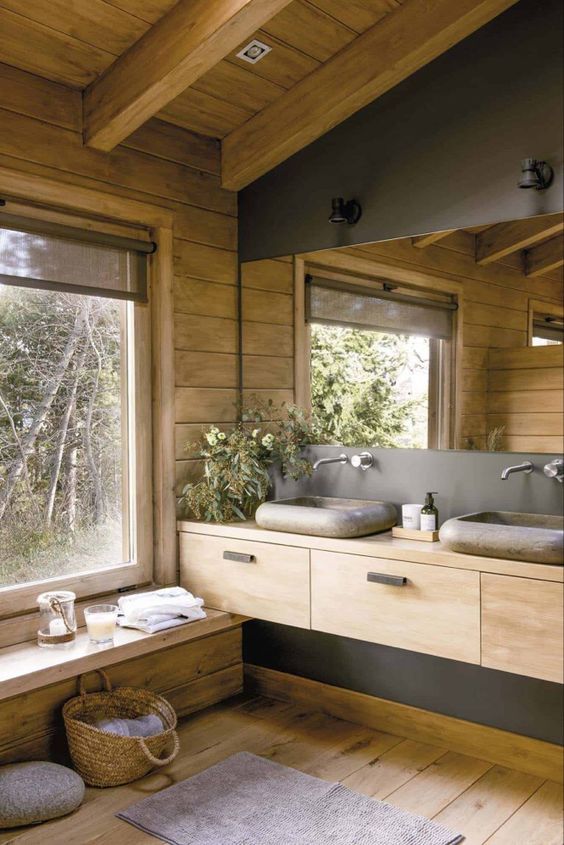 40 a cabin bathroom of wood and concrete, with stone sinks, a large mirror and a large window for a view