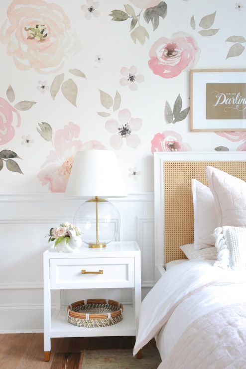 40 a lovely bedroom with a watercolor floral wall, a bed with a rattan headboard, white nightstands, gold touches