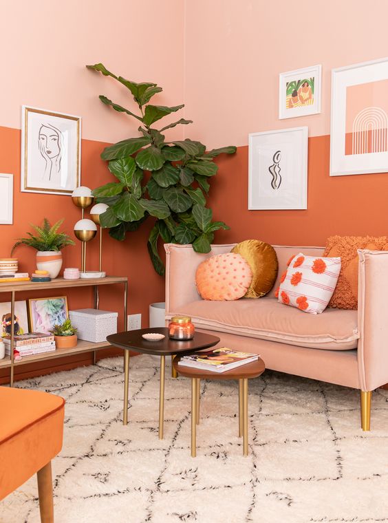 A gorgeous warm toned living room with color block walls, a blush sofa and an orange chair plus cool artworks