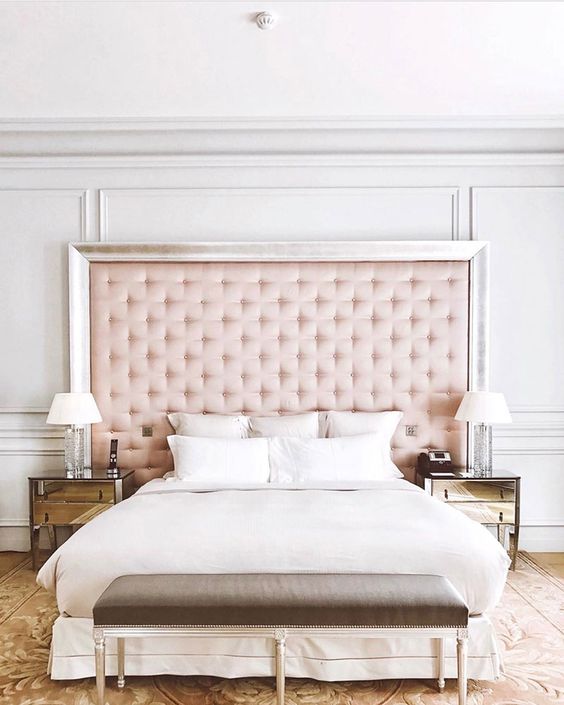 44 a glam bed with an oversized pink tufted headboard with a silver frame sets the tone in this space