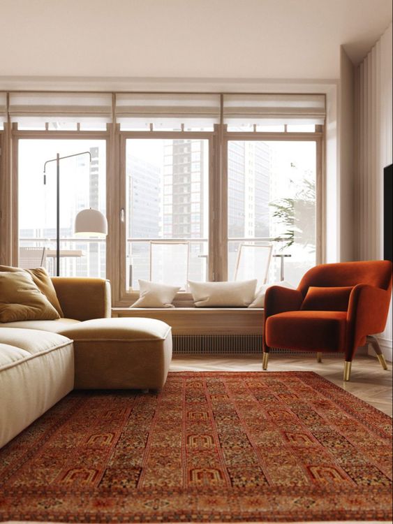 a modern and comfy living room in warm neutral tones, a neutral sofa and a burnt orange chair