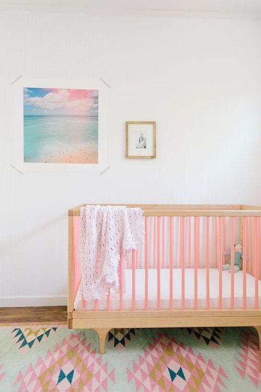 45 a pastel nursery with a pink crib, a bright pastel rug and a bold artwork is a pretty space to be