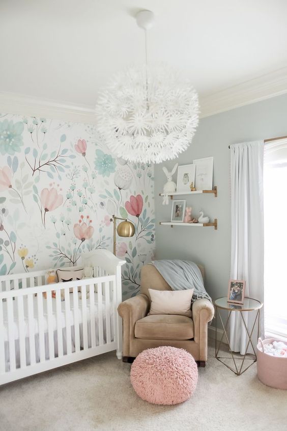 a whimsical pastel nursery with a floral accent wall, blue walls, touches of blush and pink and a floral chandelier