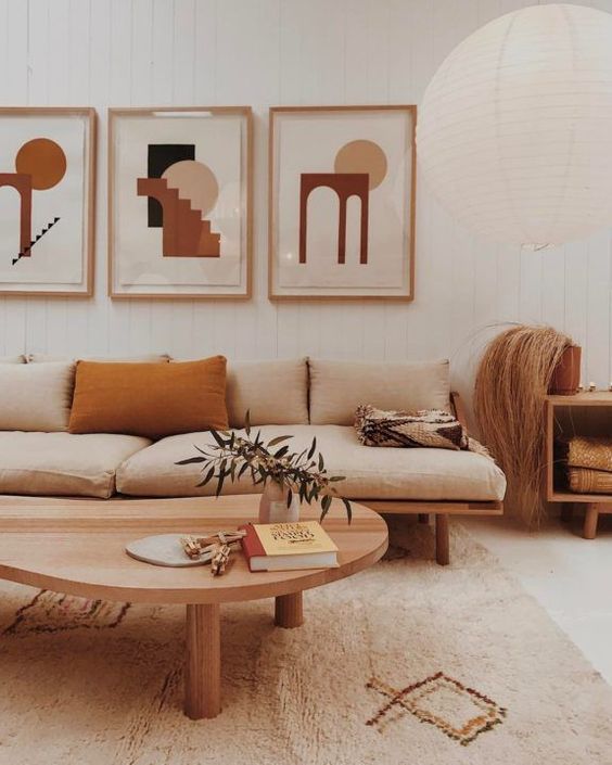 a warm-toned boho living room with chic modern furniture, a gallery wall with abstract art, a paper lamp and printed textiles