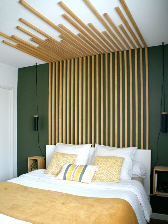 50 a statement modern bedroom with a grey wall, a white bed with an extended wooden slab headboard and yellow bedding