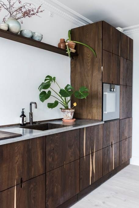 a unique Scandinavian walnut kitchen with sleek cabinets, black fixtures and grey stone countertops looks bold