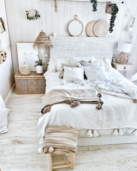 a coastal boho bedroom with a rattan bed, a chest, rattan lamps and coasters and greenery