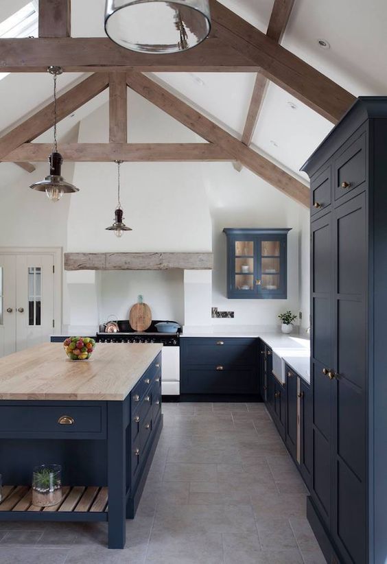 a beautiful navy farmhouse kitchen with vintage cabinets, white countertops and a large kitchen island plus a butcherblock countertop on it