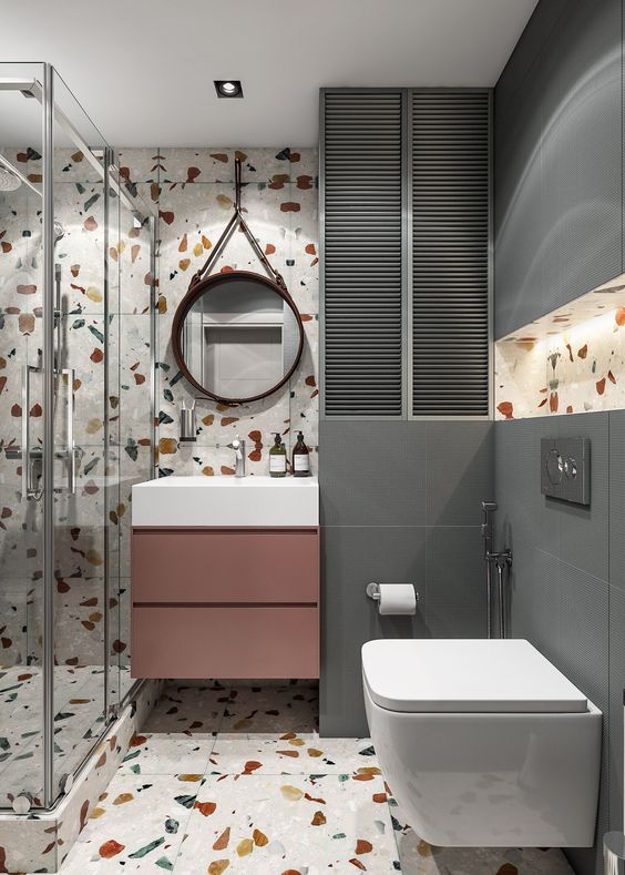a contemporary bathroom with bright terrazzo walls and a floor, grey tiles, a mauve vanity and white appliances