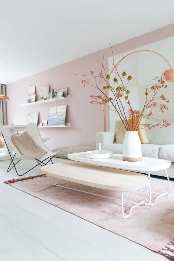 a beautiful Scandinavian living room with light pink walls, neutral furniture and branches in a vase plus a pink rug