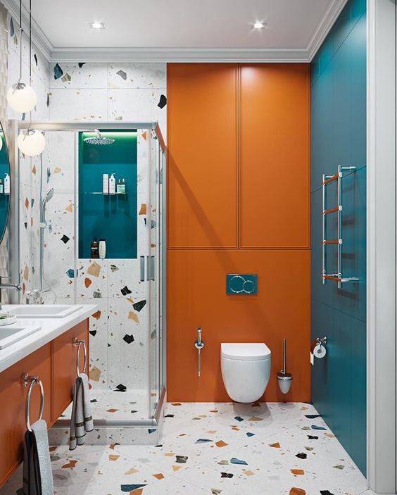 A colorful bathroom with blue and orange touches, terrazzo and white appliances and built in lights