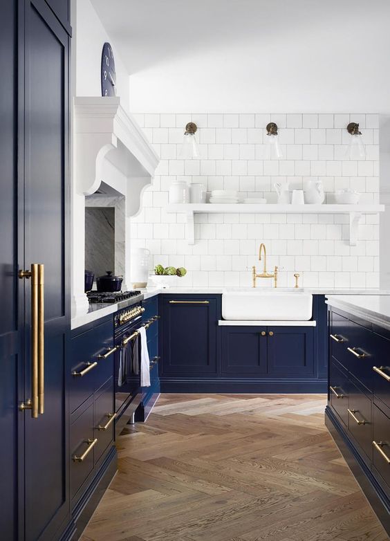 a classic Shaker-style kitchen in navy, with a white square tile backsplash and white stone countertops plus gold touches