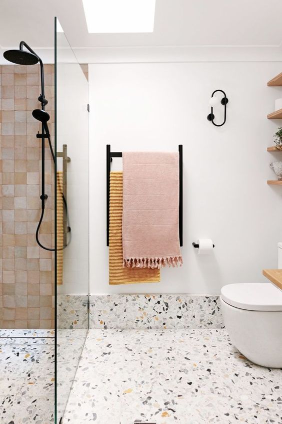 61 a contemporary bathroom with white tiles, a terrazzo floor, pink tiles, black fixtures and a skylight