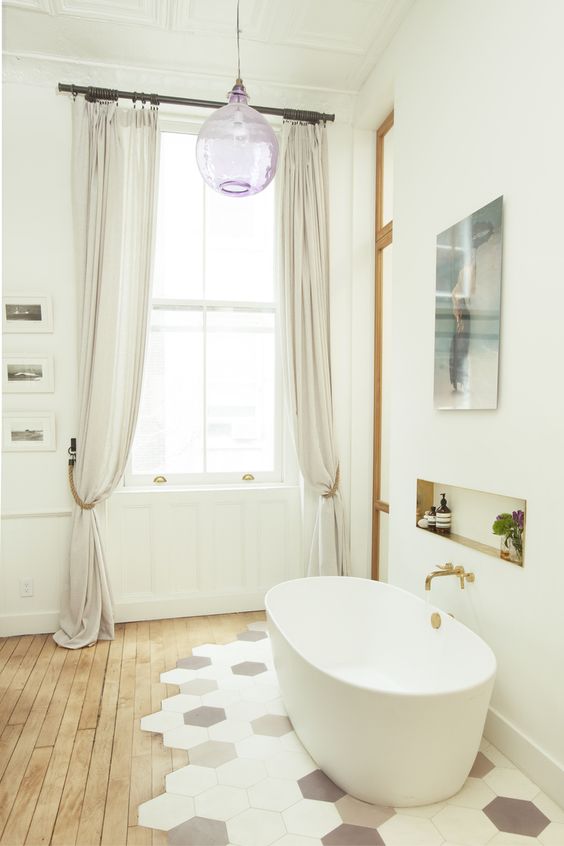 a refined bathroom with a wood floor and hex tiles, an oval tub, an artwork and a lilac pendant lamp
