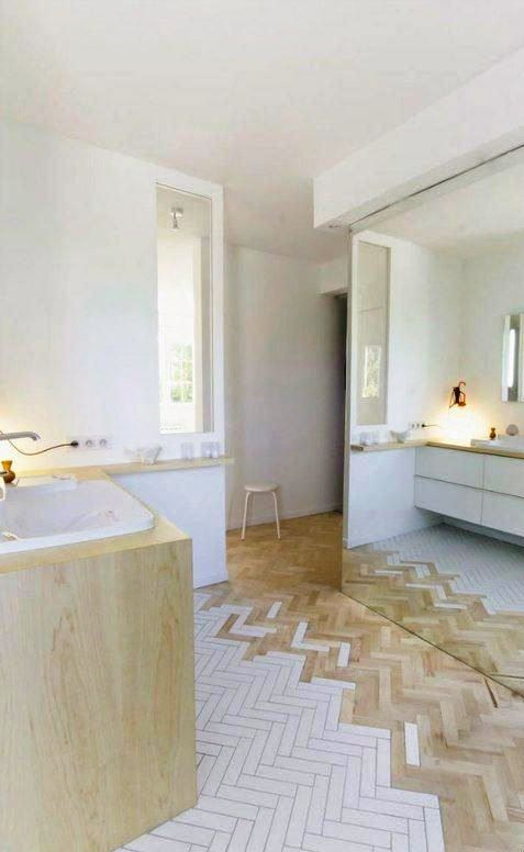 a chic contemporary bathroom in neutrals, with a wood and white tile floor, a floating vanity and a bathtub clad with wood