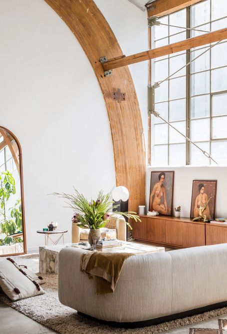 67 a catchy living room with wooden beams, a curved sofa, a marble coffee table and creative artworks