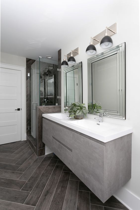 a chic bathroom with a grey sleek floating vanity, a shower space and a couple of mirrors on the wall