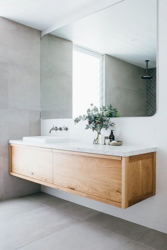 72 a contemporary bathroom with a wood and stone floating vanity, a large mirror and large scale grey tiles