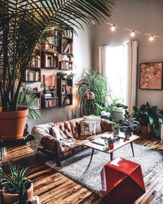73 a welcoming modern and boho living room with open box shelves, a leather sofa, a red faceted stool, potted greenery