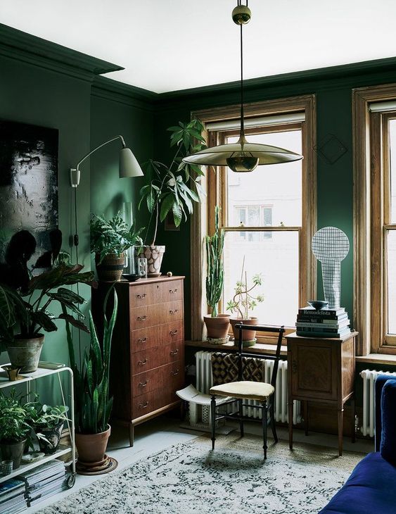 a green living room with vintage furniture, potted greenery and various lamps is a very chic space