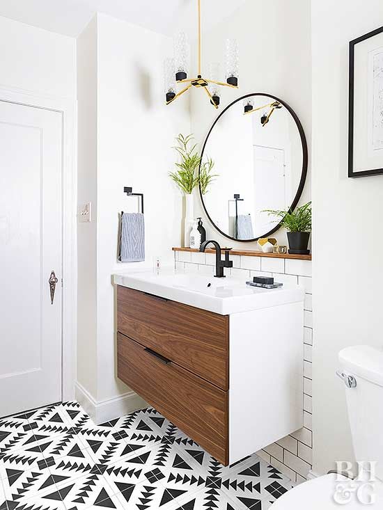 a small modern bathroom with white and black and white tiles, a floating vanity in white and rich stained wood, a round mirror