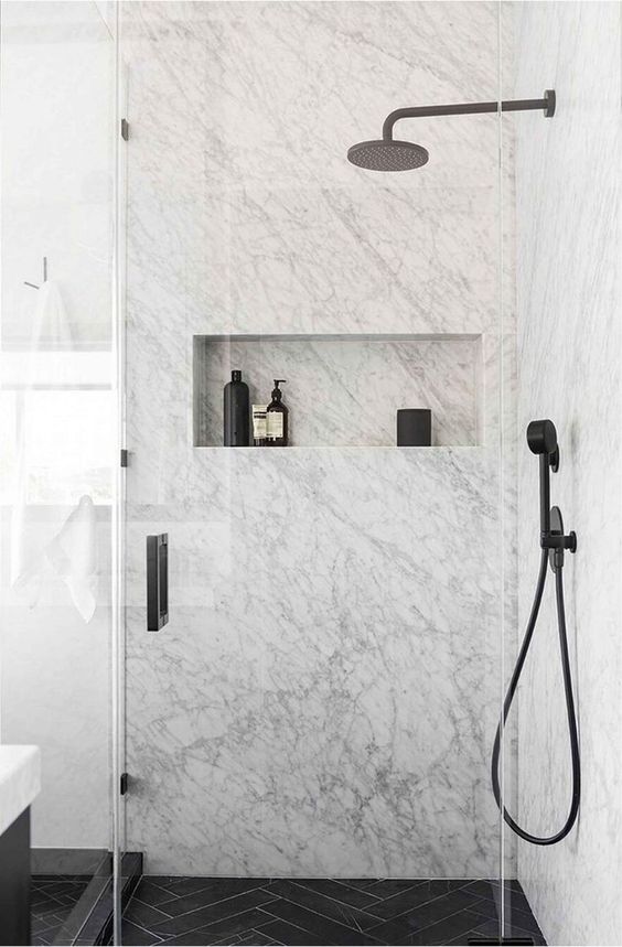 an exquisite white marble bathroom with a black chevron tile floor and black fixtures for a chic look