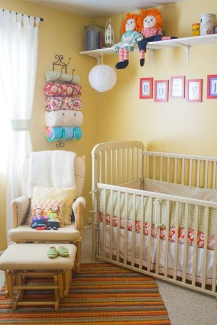 a cheery yellow nursery with vintage furniture, a shelf with toys, colorful textiles and bedding and a comfy chair with a footrest
