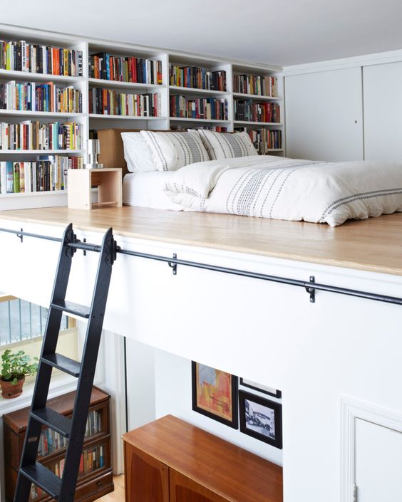 a contemporary apartment with a loft bedroom, built-in bookshelves and a mattress right on the wall