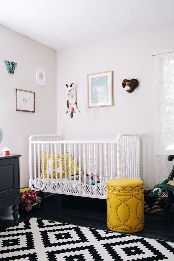 a contrasting nursery in black and white, with black and white furniture, yellow touches and a pretty gallery wall