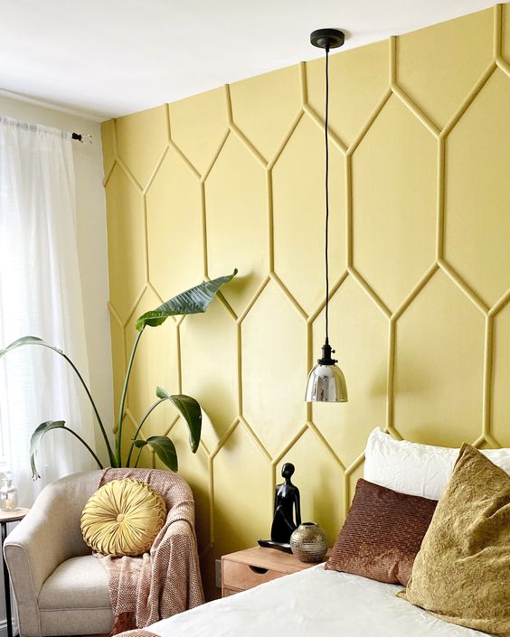 a guest bedroom accented with a yellow panel wall, with comfy and chic furniture, a pendant lamp and a potted plant