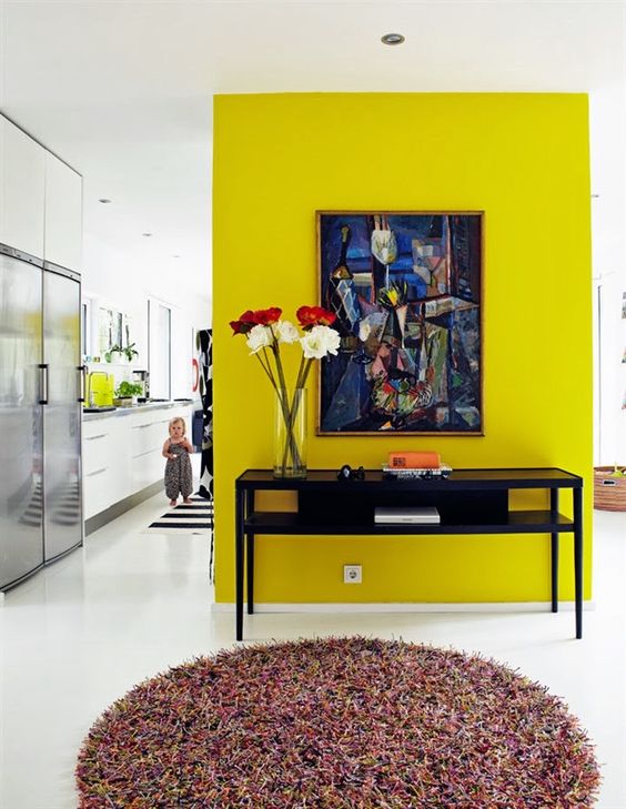 a neon yellow accent wall, a bold artwork adna vintage console table with blooms to make use of this awkward nook