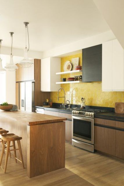 a stylish modern kitchen with black, white and stained cabinets, open shelves and a bold yellow hex tile backsplash plus a kitchen island