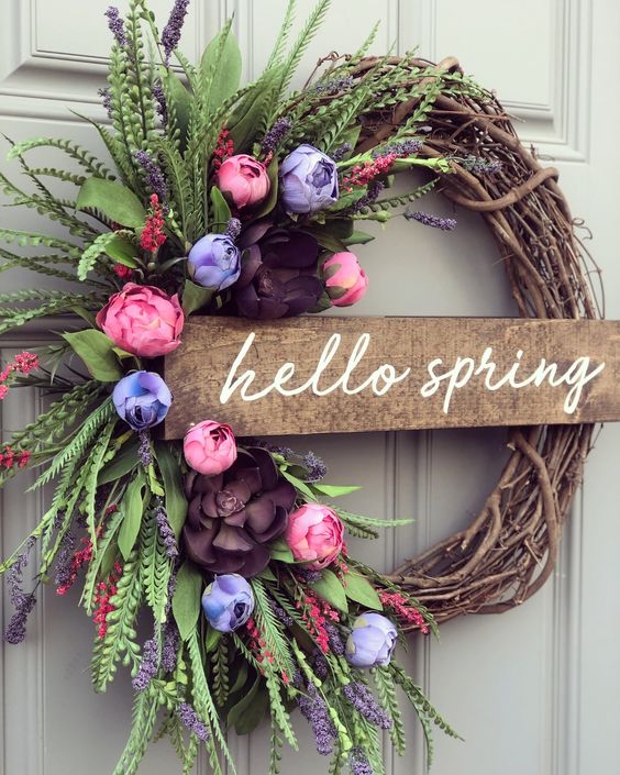 a bright and fun spring wreath of vine, a wooden plaque, bold pink, purple and blue blooms of paper and lush greenery is cool