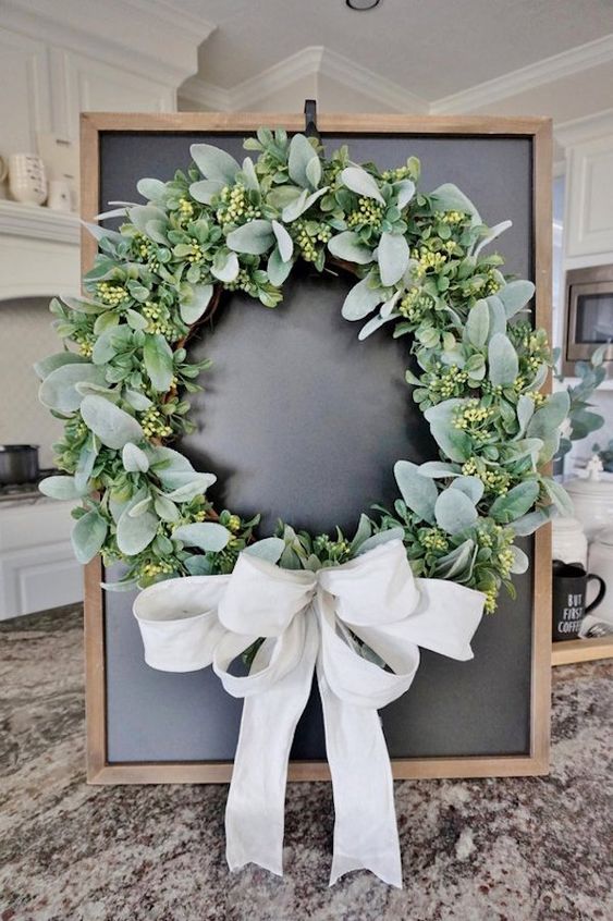 a classic greenery wreath with a large white bow is a lovely farmhouse or rustic idea for your front door