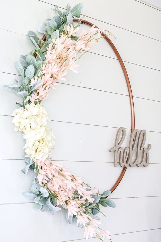 a fresh and pretty spring wreath of a large hoop, faux greenery, white and pink blooms and with a HELLO piecde